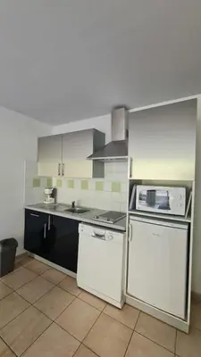 a kitchen with a white refrigerator and a stove at Appartement climatisé dans une résidence avec piscine mer à pied in Serra-di-Ferro