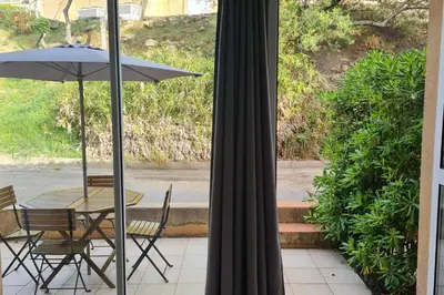 a table and chairs with an umbrella on a patio at Appartement climatisé dans une résidence avec piscine mer à pied in Serra-di-Ferro