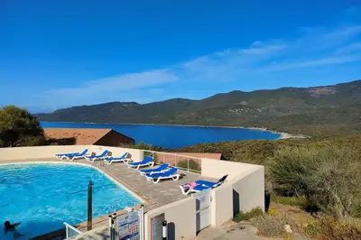a pool with lounge chairs and a view of the water at Appartement 225 in Serra-di-Ferro