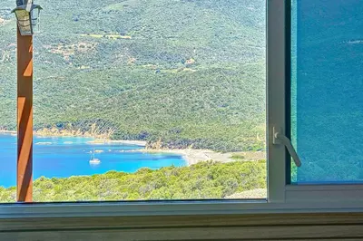 a window with a view of a beach and the ocean at Magnifique T2 terrasse vue mer panoramique dans résidence avec piscine in Serra-di-Ferro