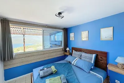 a blue bedroom with a bed and a window at Magnifique T2 terrasse vue mer panoramique dans résidence avec piscine in Serra-di-Ferro