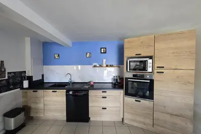a kitchen with wooden cabinets and a black appliances at Magnifique T2 terrasse vue mer panoramique dans résidence avec piscine in Serra-di-Ferro