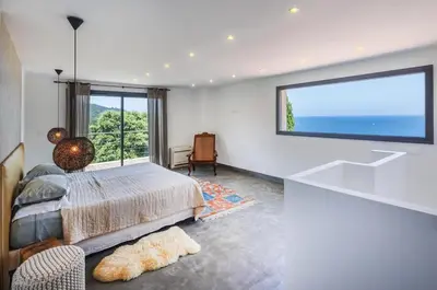 a bedroom with a bed and a large window at Villa 10 personnes avec piscine vue mer in Conca