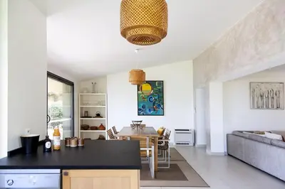 a kitchen and living room with a table and a couch at Villa 10 personnes avec piscine vue mer in Conca