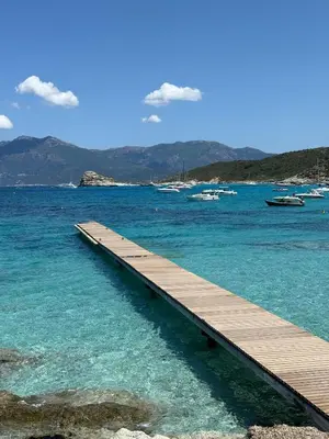a wooden pier in the water with boats in the water at Appartement 2 CHAMBRES PISCINE TERRASSE SAINT FLORENT in Oletta
