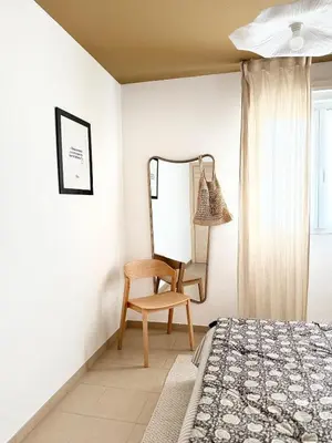 a bedroom with a bed and a chair and a mirror at Appartement 2 CHAMBRES PISCINE TERRASSE SAINT FLORENT in Oletta