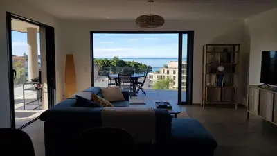 a living room with a couch and a view of the ocean at Appartement T3 Porticcio résidence les Jardins de Livia in Albitreccia