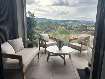 a balcony with a couch and chairs and a table at Appartement T3 Porticcio résidence les Jardins de Livia in Albitreccia