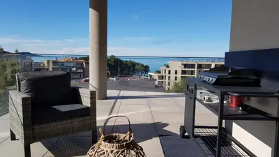 a balcony with a chair and a grill with a view at Appartement T3 Porticcio résidence les Jardins de Livia in Albitreccia