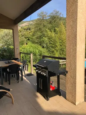 a grill on a deck with a table and chairs at villa paisible de campagne avec piscine in Alata