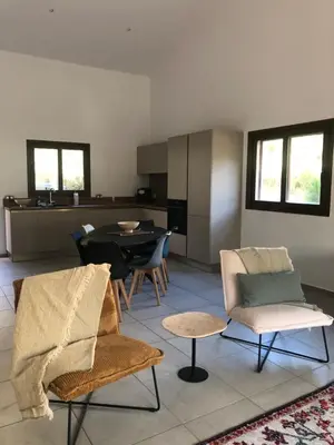 a living room with chairs and a table and a kitchen at villa paisible de campagne avec piscine in Alata
