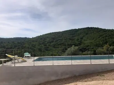 a swimming pool behind a fence next to a mountain at CATALINA 2-MYRTHA- Piscine en résidence- vue mer- plage à pieds in Conca