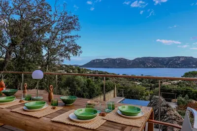 a wooden table on a deck with a view of the water at Villa Marina Di Porto-Vecchio in Porto-Vecchio