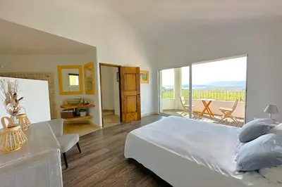 a bedroom with a large bed and a balcony at Villa Dolce Di Cirendinu in Sainte-Lucie de Porto-Vecchio