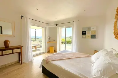 a bedroom with a bed and a sliding glass door at Villa Dolce Di Cirendinu in Sainte-Lucie de Porto-Vecchio