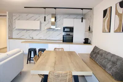 a kitchen and living room with a wooden table and a couch at Superbe Appartement port de Bonifacio in Bonifacio