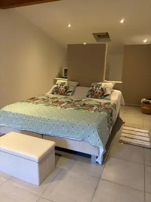 a bedroom with a large bed and a stool at villa paisible à la campagne in Alata
