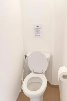 a bathroom with a toilet with a sign on the wall at Villa vue jardin dans résidence calme wifi piscine mer à pied in Serra-di-Ferro