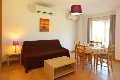a living room with a couch and a table at Villa vue jardin dans résidence calme wifi piscine mer à pied in Serra-di-Ferro