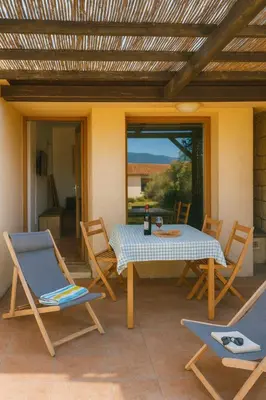 a patio with a table and chairs on a patio at Villa vue jardin dans résidence calme wifi piscine mer à pied in Serra-di-Ferro