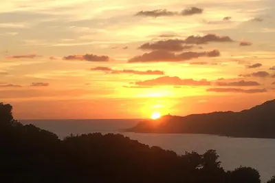 a sunset with the sun setting over the ocean at Mini villa vue jardin dans résidence calme wifi piscine mer à pied in Serra-di-Ferro