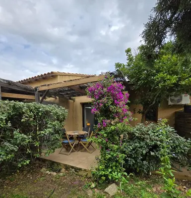 a patio with a table and purple flowers at Mini villa vue jardin dans résidence calme wifi piscine mer à pied in Serra-di-Ferro