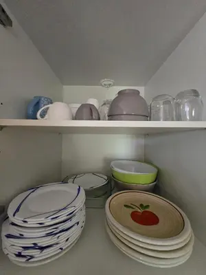 a shelf filled with plates and bowls and bowls at Mini villa vue jardin dans résidence calme wifi piscine mer à pied in Serra-di-Ferro