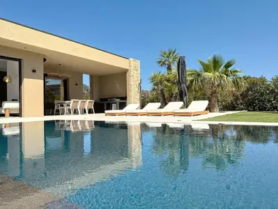 a swimming pool with chairs and a house at Casa Jean Baptiste in Lecci