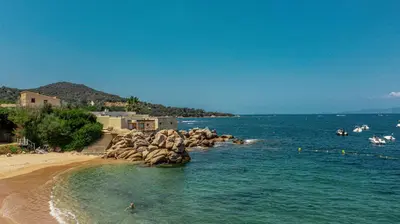 a beach with a group of people in the water at camping la vallée in Coti-Chiavari