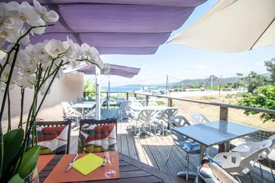 a balcony with tables and chairs and a view of the beach at camping la vallée in Coti-Chiavari