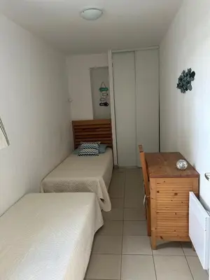 a room with two beds and a wooden table at Joli appartement résidentiel plage et piscine in Poggio-Mezzana