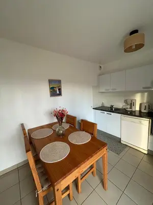 a kitchen with a wooden table with chairs and a kitchen at Joli appartement résidentiel plage et piscine in Poggio-Mezzana