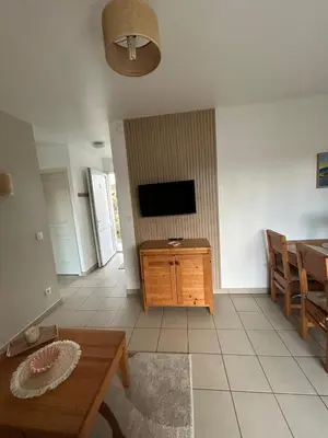 a living room with a television and a table at Joli appartement résidentiel plage et piscine in Poggio-Mezzana