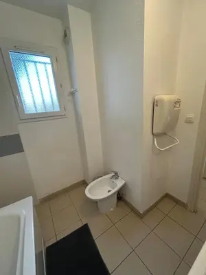 a bathroom with a toilet and a window at Joli appartement résidentiel plage et piscine in Poggio-Mezzana