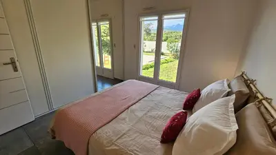 a bedroom with a bed with red pillows and a window at RUNDINELLE-Piscine privée- clim-wifi-plage à pieds in Solaro