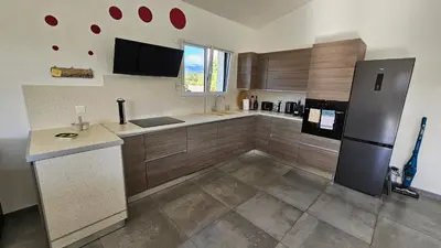 a kitchen with wooden cabinets and a stainless steel refrigerator at RUNDINELLE-Piscine privée- clim-wifi-plage à pieds in Solaro