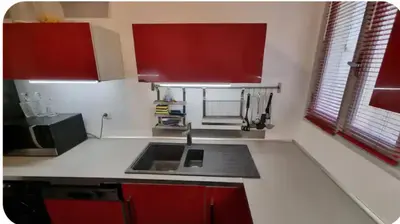 a small kitchen with a sink and red cabinets at F2 idéalement placé route des sanguinaires in Ajaccio