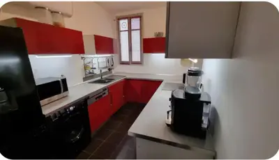 a kitchen with red cabinets and a black appliance at F2 idéalement placé route des sanguinaires in Ajaccio