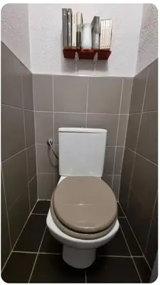 a bathroom with a toilet with a shelf on the wall at F2 idéalement placé route des sanguinaires in Ajaccio
