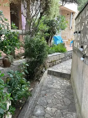 a garden with a stone walkway next to a house at Appartement cosy à Propriano, 45 m², terrasse in Propriano
