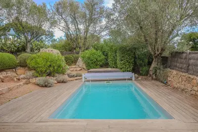 a swimming pool with a bench in a garden at La bergerie de Sotta in Sotta