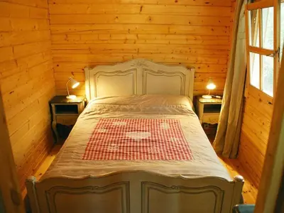 a bed in a wooden room with two tables and two lamps at Cabin in Montegrosso with Wi-Fi in Montegrosso