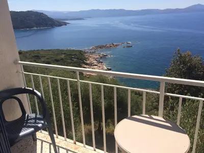 a balcony with a chair and a view of the ocean at Bel Mare in Cargèse