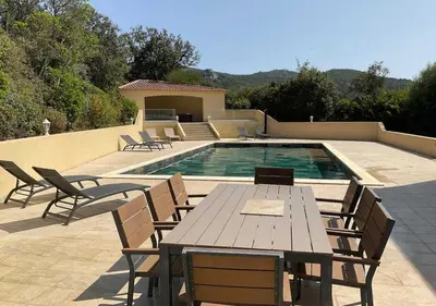 a patio with a table and chairs next to a pool at Villa Vitalba - Le charme corse avec piscine in Sartène