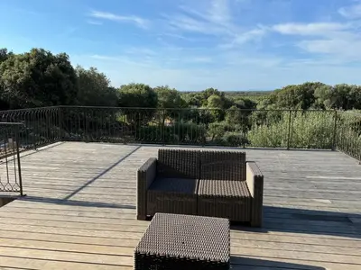 a deck with a couch and chairs on a wooden deck at Villa Ratino in Bonifacio
