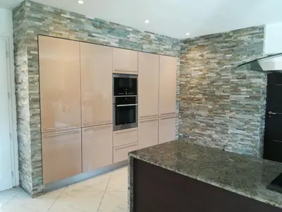 a kitchen with stainless steel cabinets and a brick wall at Villa 300m2 piscine chauffée et jacuzzi-spa de nage in Afa