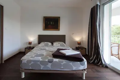 a bedroom with a bed and a large window at Villa 300m2 piscine chauffée et jacuzzi-spa de nage in Afa