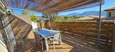 a wooden deck with a table and chairs on it at Duo de Mini-villas, gîtes chaleureux & vue mer in Olmeto