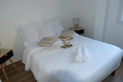 a white bed with two towels and slippers on it at Duo de Mini-villas, gîtes chaleureux & vue mer in Olmeto