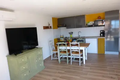 a kitchen and dining room with a table and a television at Duo de Mini-villas, gîtes chaleureux & vue mer in Olmeto